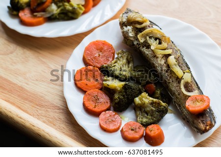 Baked roasted fried fish with baked, baked, gifted vegetables on a wooden table