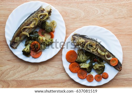 Baked roasted fried fish with baked, baked, gifted vegetables on a wooden table