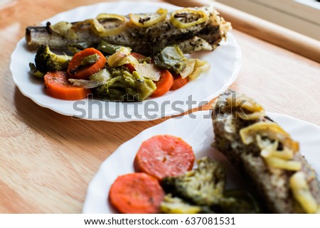 Baked roasted fried fish with baked, baked, gifted vegetables on a wooden table
