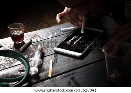 Disease concept. No to drugs concept. Drug addict using drugs with help of mobile or smart phone. Drug addict man alone.