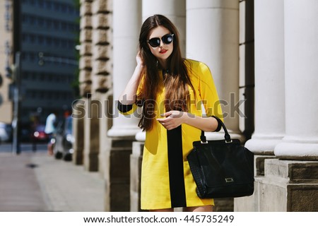 chân dung ngoài trời của trẻ phụ nữ xinh đẹp đi bộ trên đường phố. Mẫu đeo kính mát & thời trang màu vàng mùa hè. Cô gái nhìn xuống. Nữ thời trang khái niệm. Thành phố sống. Ngày nắng. thắt lưng lên