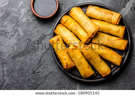 Fried spring rolls on black iron plate on grey stone slate background. Top view, copy space