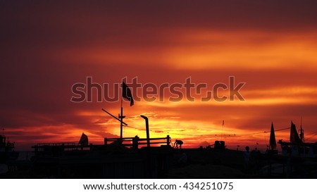 LY SON ISLAND, VIETNAM - JUNE 2016 : Beautiful sunset over boats on the sea of Ly Son island, Quang Ngai province, Vietnam. Flag and crane waving in the red sky. Revolution abstract. Sihouette.