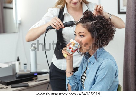 cheerful woman in the Barber shop with beautiful unusual curly hair drinking coffee or tea.