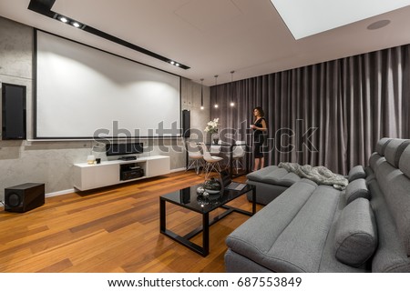 Woman In Living Room With Projector Screen Gray Sofa And Black Coffee Table Woman In Living Room With Projector Screen Gray Sofa And Black Coffee Table