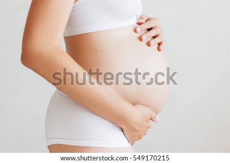 Pregnant woman in white underwear. Young woman expecting a baby.