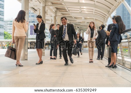 Middle-aged businessman carrying a briefcase, running in a hurry to go to work among the people walking in city.