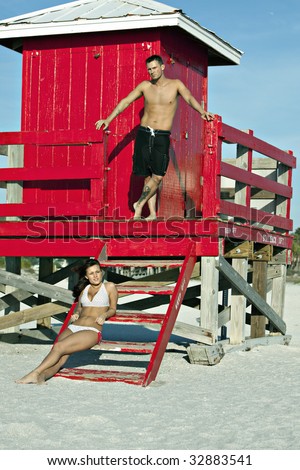 https://thumb7.shutterstock.com/display_pic_with_logo/387685/387685,1246330579,1/stock-photo-handsome-man-standing-on-red-lifeguard-tower-at-beach-with-sexy-bikini-clad-woman-sitting-on-steps-32883541.jpg