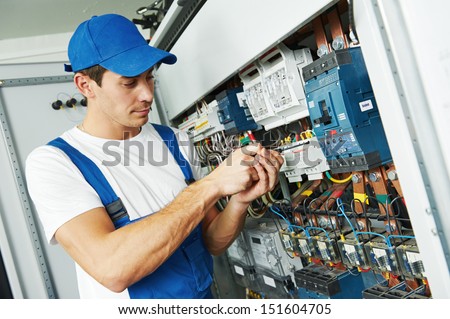Young adult electrician builder engineer screwing equipment in fuse box