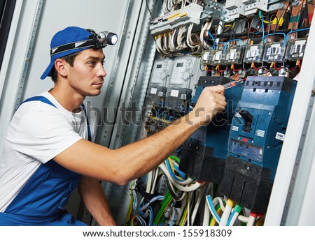 Young adult electrician builder engineer screwing equipment in fuse box