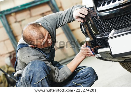 auto mechanic worker sanding polishing bumper car at automobile repair and renew service station shop by sandpaper