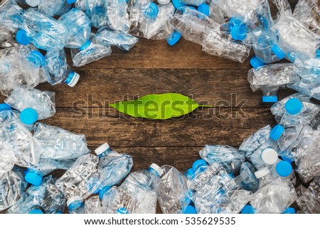 Recycling concept. Green leaves on a wooden background around the transparent plastic bottles. The problem of ecology, environmental pollution.