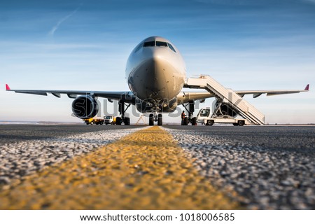 Front view of passenger airplane and boarding stairs at the airport apron