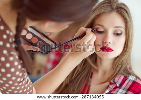 make up artist doing professional make up of young woman