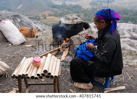 HOA BINH, Vietnam, January 12, 2016 Thai ethnic woman, sits embroidery, the pot of food, with a cow in the distance stood watching. peaceful scene