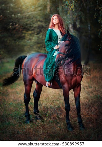 stock photo beautiful red haired girl in green medieval dress sitting on a horse and looking afar fairy tale 530899957
