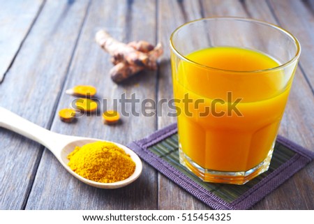 Close up of immunity boosting spicy turmeric juice and powder on a wooden table.