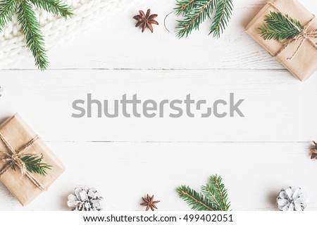 Christmas composition. Christmas gift, knitted blanket, pine cones, fir branches on wooden white background. Flat lay, top view