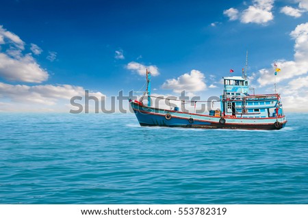 Fishing boats are overwhelmingly in the midst of the sea on a beautiful blue sky.
