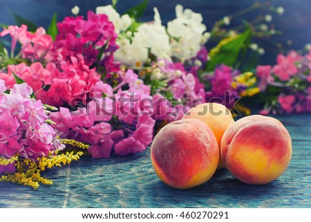Summer ripe red peach fruits on the rustic wooden board with colorful flowers, organic eco local food natural concept in hipster style