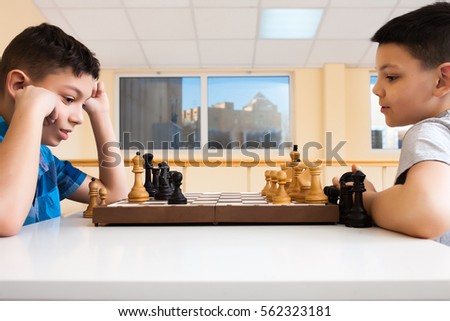 Children playing chess at the table. the concept of childhood and board games, brain development and logic