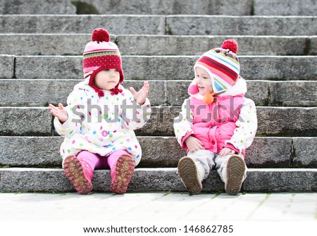 two funny girls sitting on the stairs - stock photo