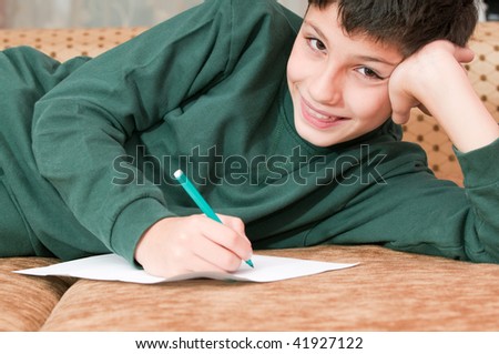 A smiling boy is writing a letter