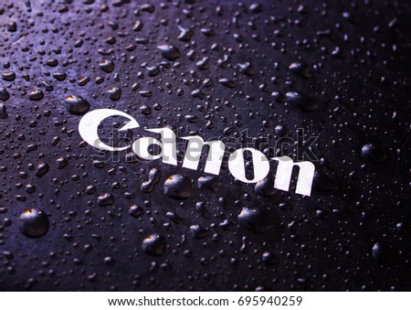 Water drops close-up on a photographic equipment logo CANON