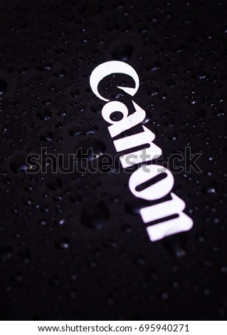 Water drops close-up on a photographic equipment logo CANON