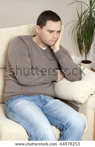 stock-photo-man-sitting-at-home-on-sofa-looking-miserable-64878253.jpg