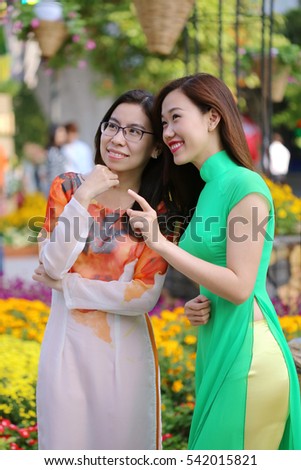 Nguyen Hue walking street, Ho Chi Minh city, Vietnam - February 07, 2016: Vietnamese young girls are smiling and looking at flower pots in a spring fair, the days before Vietnamese Tet holiday.