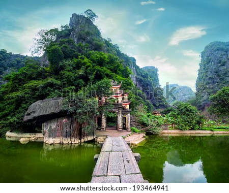 Outdoor park landscape with lake and stone bridge. Gate entrance to ancient Bich Dong pagoda complex. Ninh Binh, Vietnam travel destination