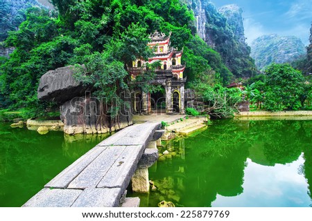 Outdoor park landscape with lake and stone bridge. Gate entrance to ancient Bich Dong pagoda complex. Ninh Binh, Vietnam travel destination