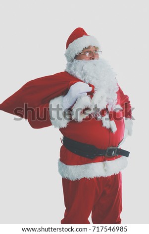 Real Santa Claus carrying big bag full of gifts, isolated on white background.