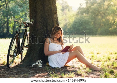 https://thumb7.shutterstock.com/display_pic_with_logo/438058/145944995/stock-photo-beautiful-young-woman-portrait-reading-a-book-under-a-tree-with-bicycle-in-the-park-145944995.jpg