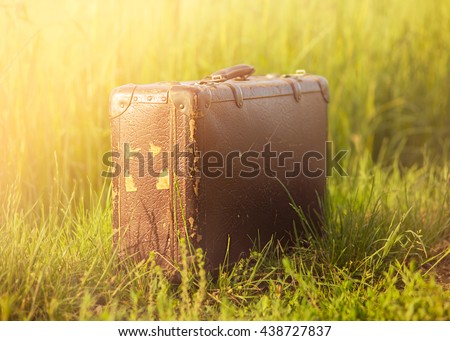 Forsaken abandoned old vintage luggage suitcase on the field summer sun light