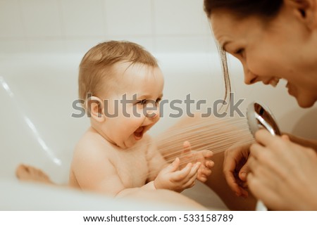 Mother washing shower happy newborn baby in bath