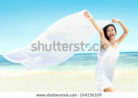 Travel and Vacation. Freedom Concept. Beautiful Girl With White Scarf on The Beach enjoying summer.