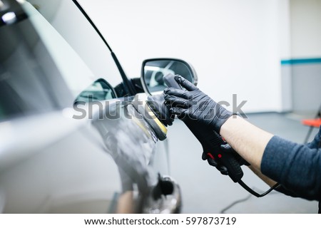 Car detailing - Hands with orbital polisher in auto repair shop. Selective focus.