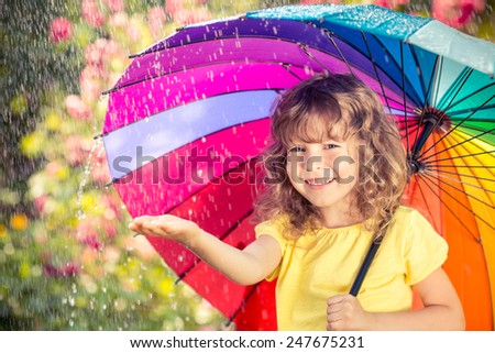 Happy child in the rain. Funny kid playing outdoors in spring park