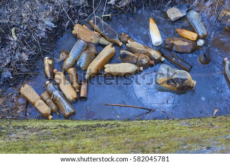Landfill (plastic bottles) into the river. Environmental pollution.