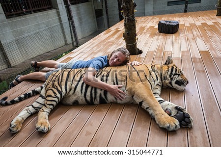 Young man hugging a big tiger in Thailand - stock photo