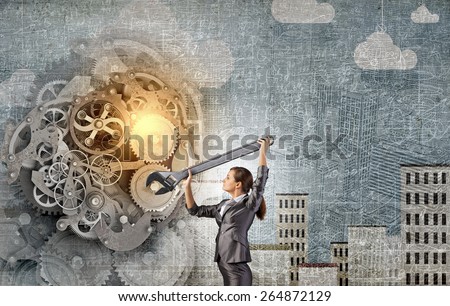 Young businesswoman fixing gears mechanism with wrench