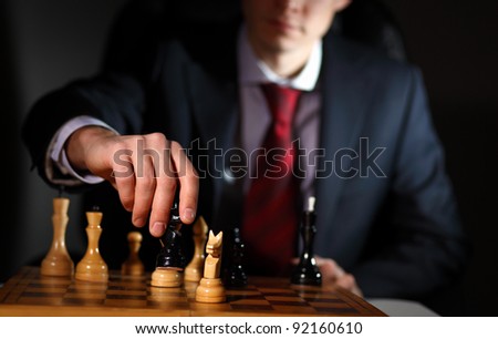 Image of a businessman in dark suit playing chess