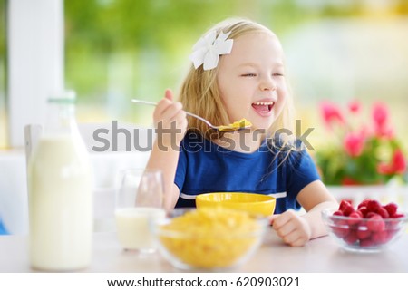 cute little girl enjoying her breakfast at home pretty child eating corn flakes and raspberries - Pictures Of Small Children cute little girl enjoying her breakfast at home pretty child eating corn flakes and raspberries - Pictures Of Small Children