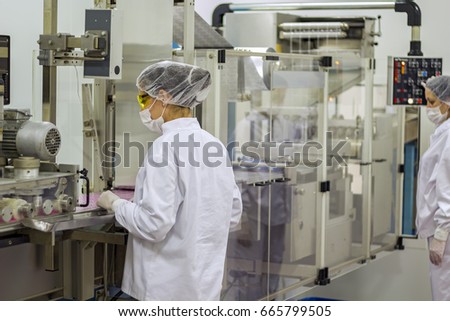Two Female Workers Controlling the Production in Pharmaceutical Factory.
An employee oversees the packaging of the medical pills. Pharmaceutical technologist wearing protective clothing.