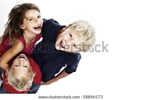 Group of laughing children hugging each other and looking up, isolated on white background with copy-space, top view.