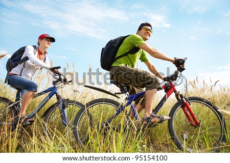 Couple of cyclists riding bicycles in meadow