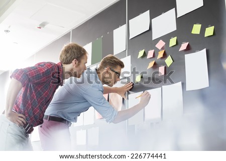 Businessmen analyzing documents on wall in office