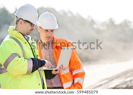Supervisors using laptop at construction site